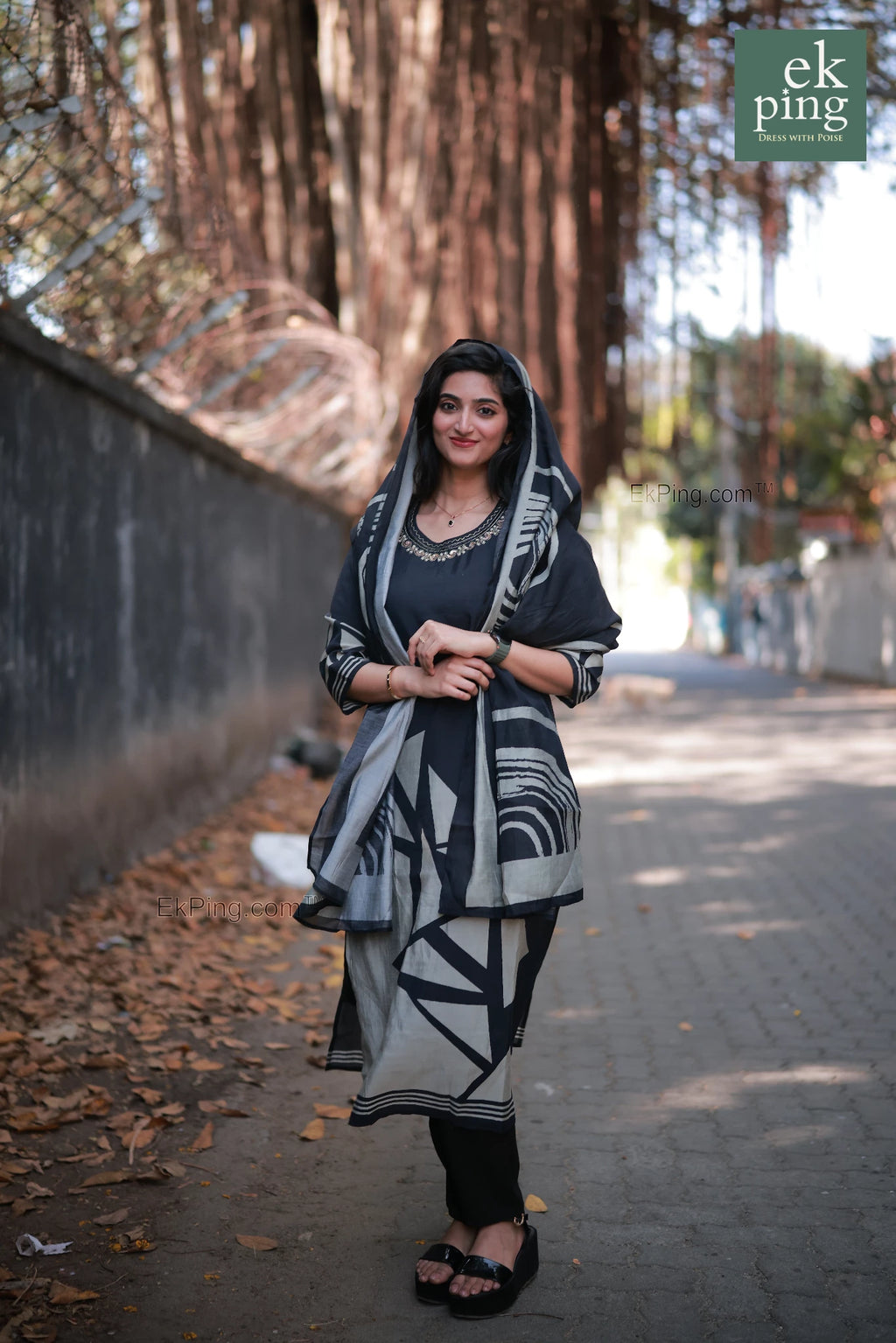 Woman in a black daily wear long kurti and salwar set standing outdoors with trees in the background