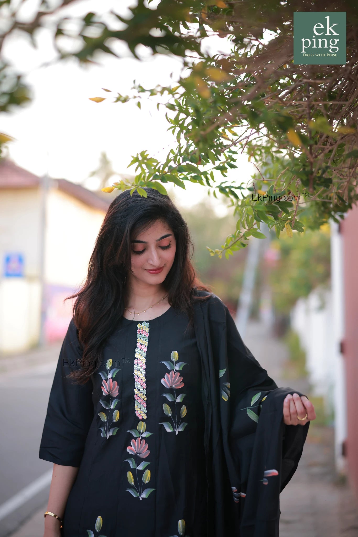 Woman wearing a black salwar set standing outdoors with blurred background