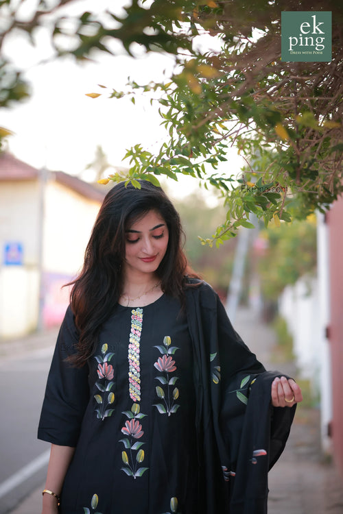 Woman wearing a black salwar set standing outdoors with blurred background