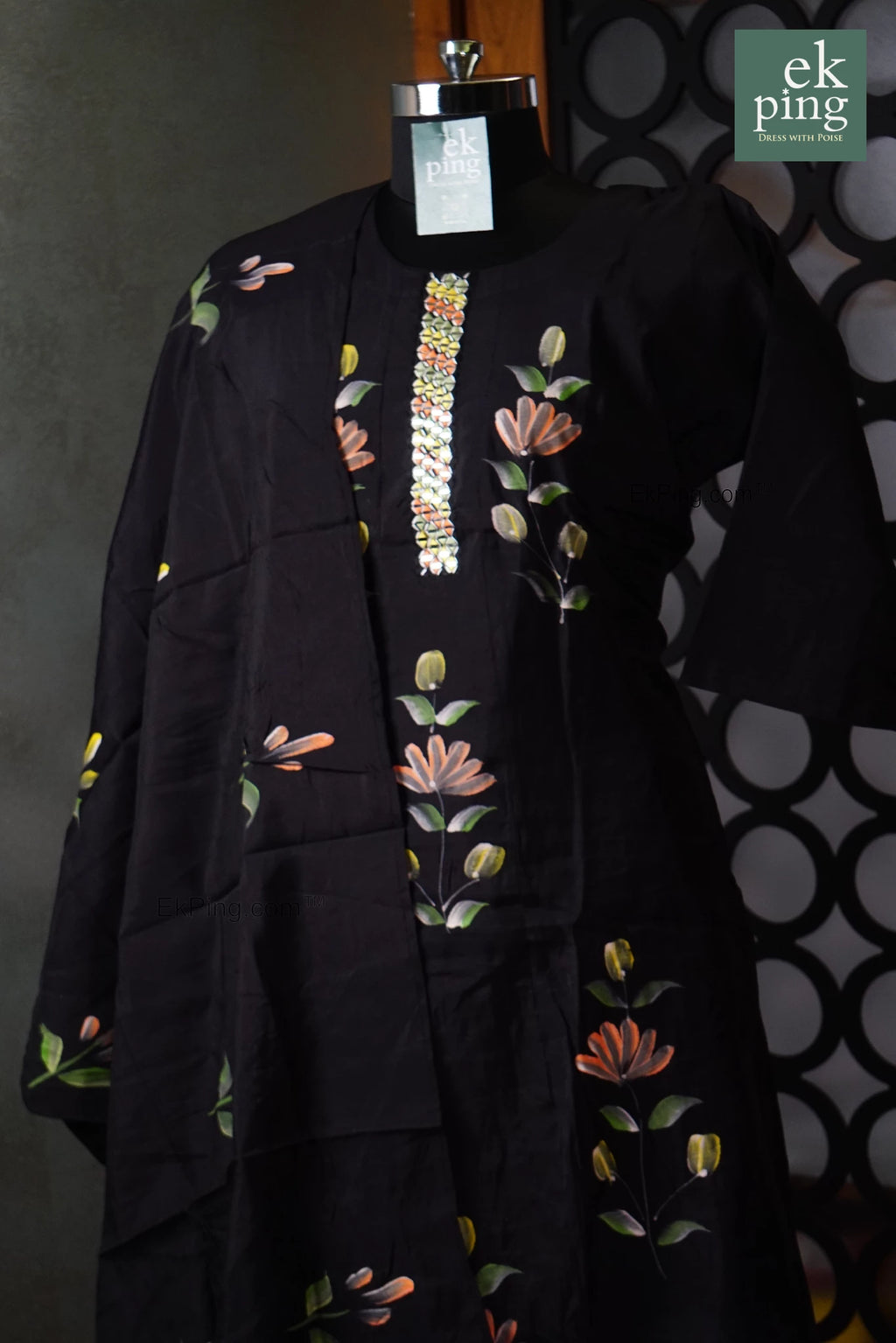 Black salwar set with floral embroidery on a manequin against a dark background