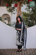 Woman holding a black and white patterned salwar kurti outdoors with greenery in the background