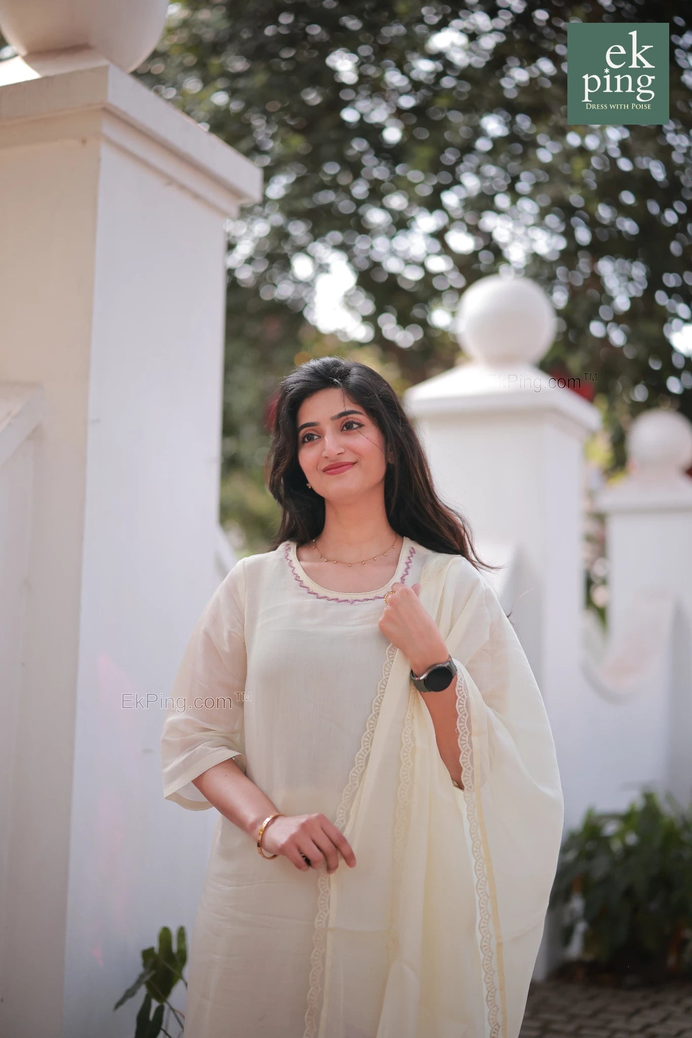 Girl wearing Chanderi Off-White Salwar Set with matching Dupatta modelling on streets with a compound wall in back