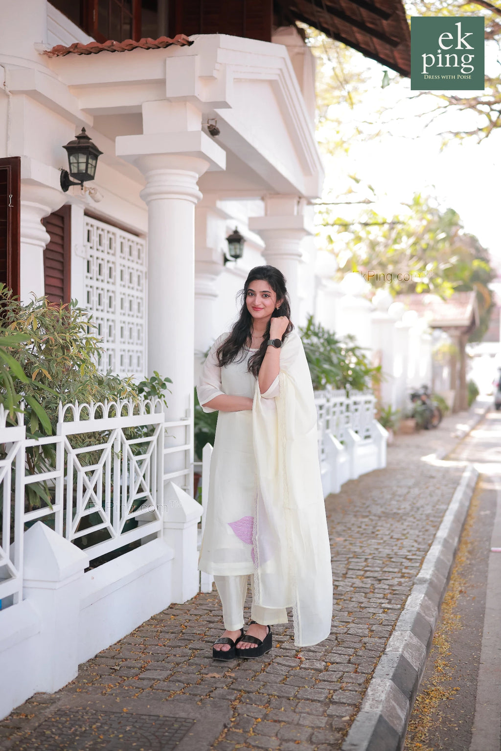 Girl wearing Chanderi Off-White Salwar Set with matching Dupatta smiling in front of a colonial bunglow in fort kochi