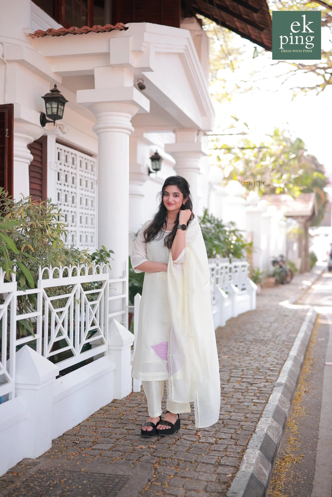 Girl wearing Chanderi Off-White Salwar Set with matching Dupatta smiling in front of a colonial bunglow in fort kochi