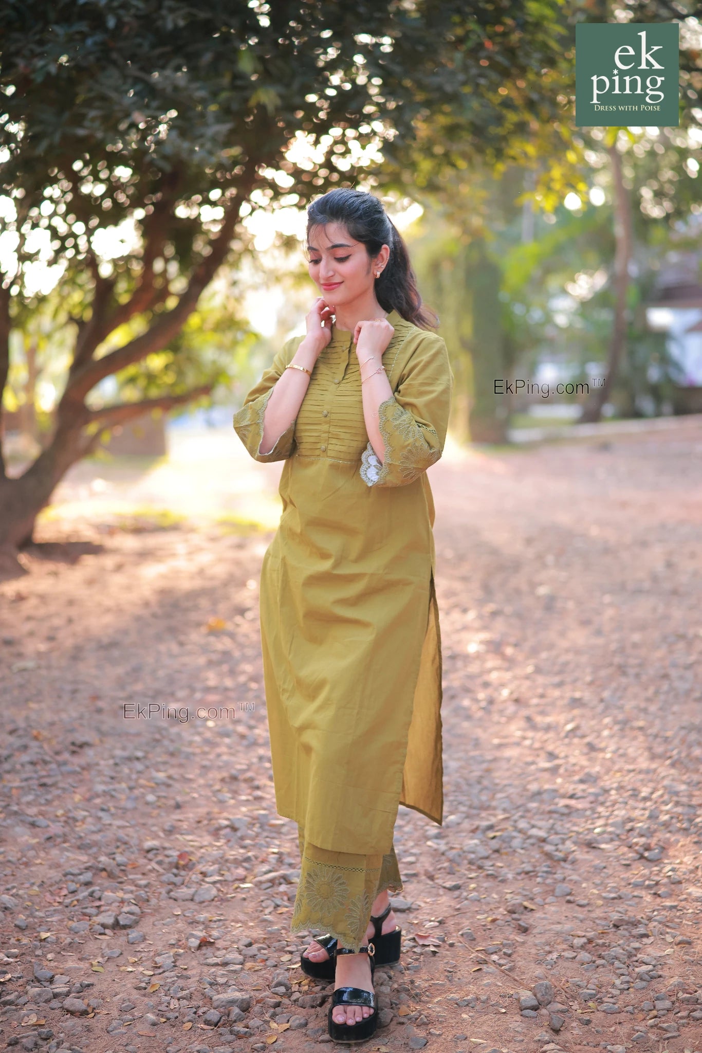 Woman in a green co-ord set standing outdoors with trees in the background