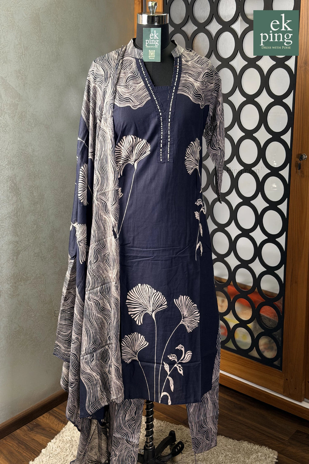 Navy dress with floral pattern and matching shawl on a manequin against a decorative wall.