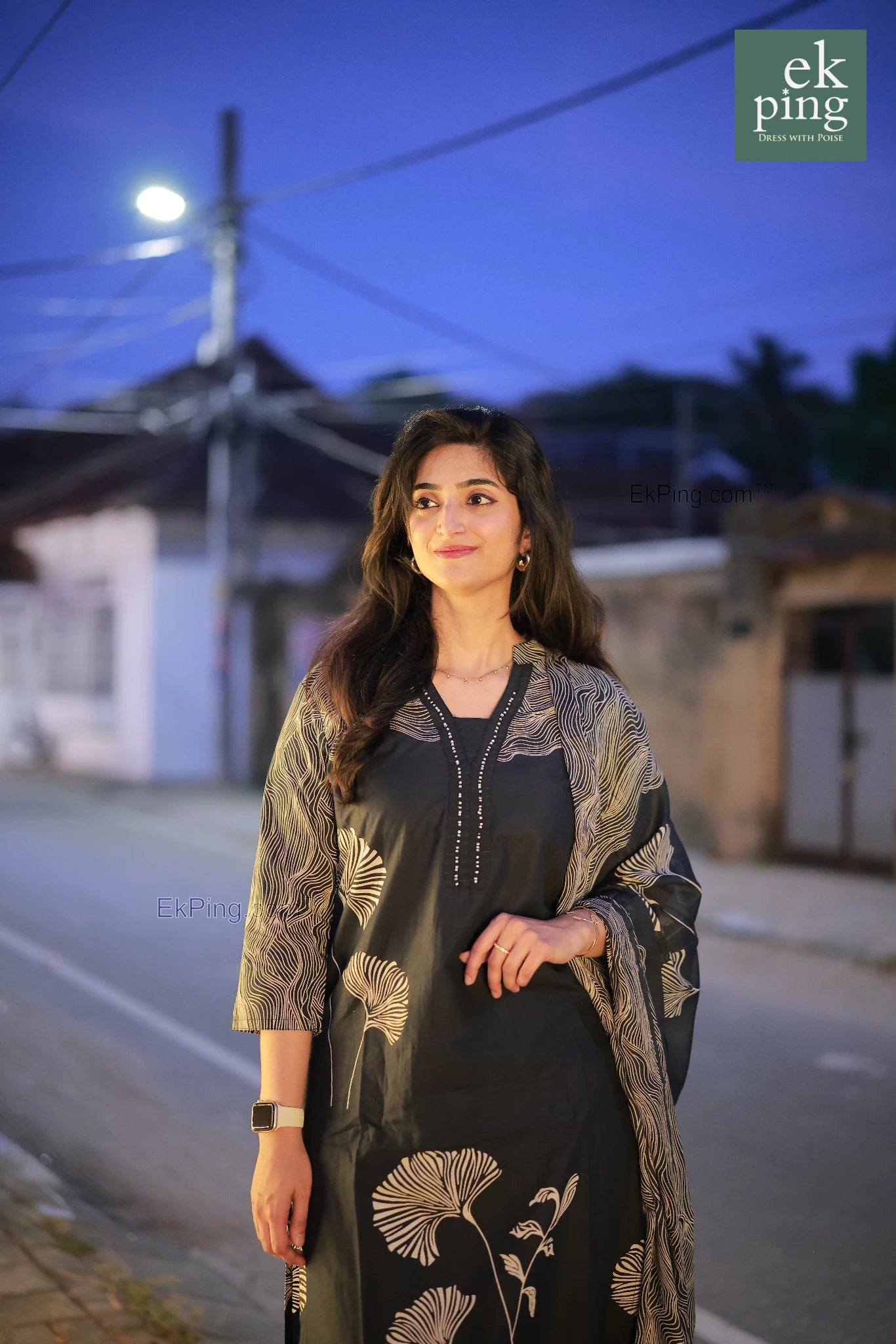 Woman in a navy black salwar kurti standing on a street at night.