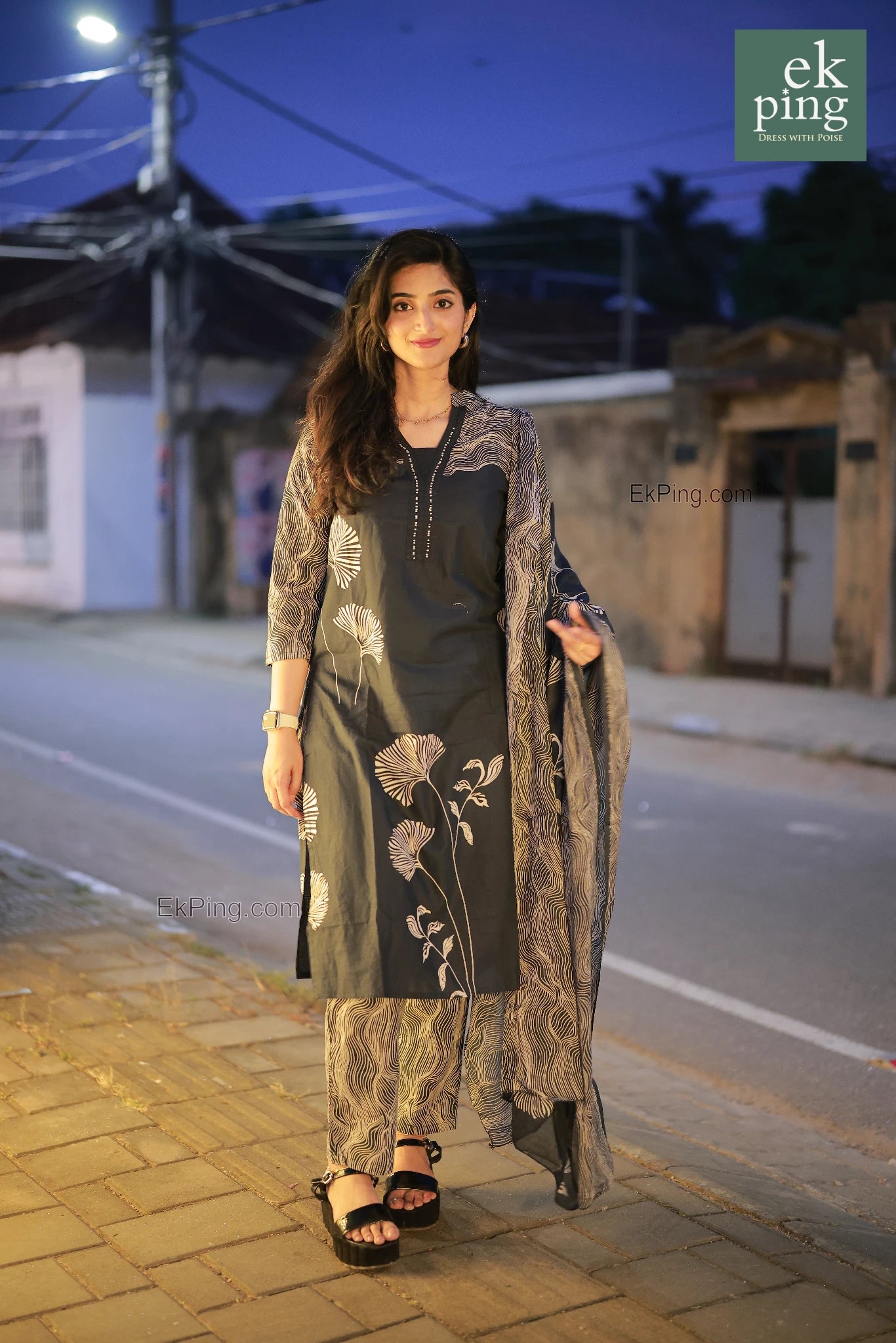 Woman in navy black salwar kurti  standing on a street at night.