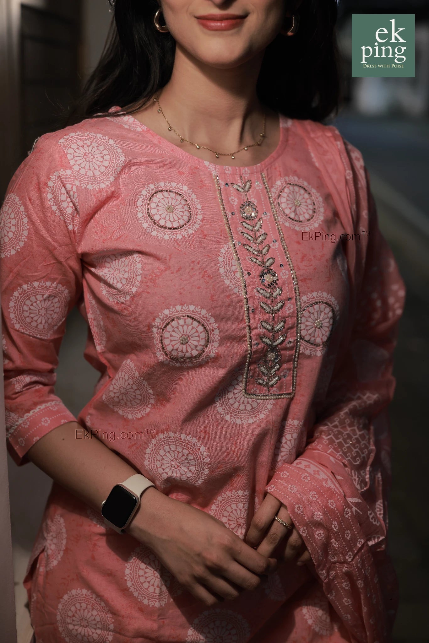 Girl wearing a pink cotton salwar set with intricate patterns, brand 'ek ping' visible.