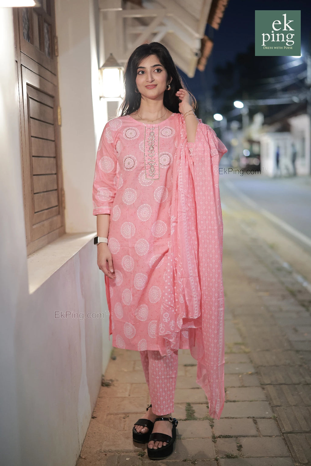Woman in a pink cotton salwar set standing on a street