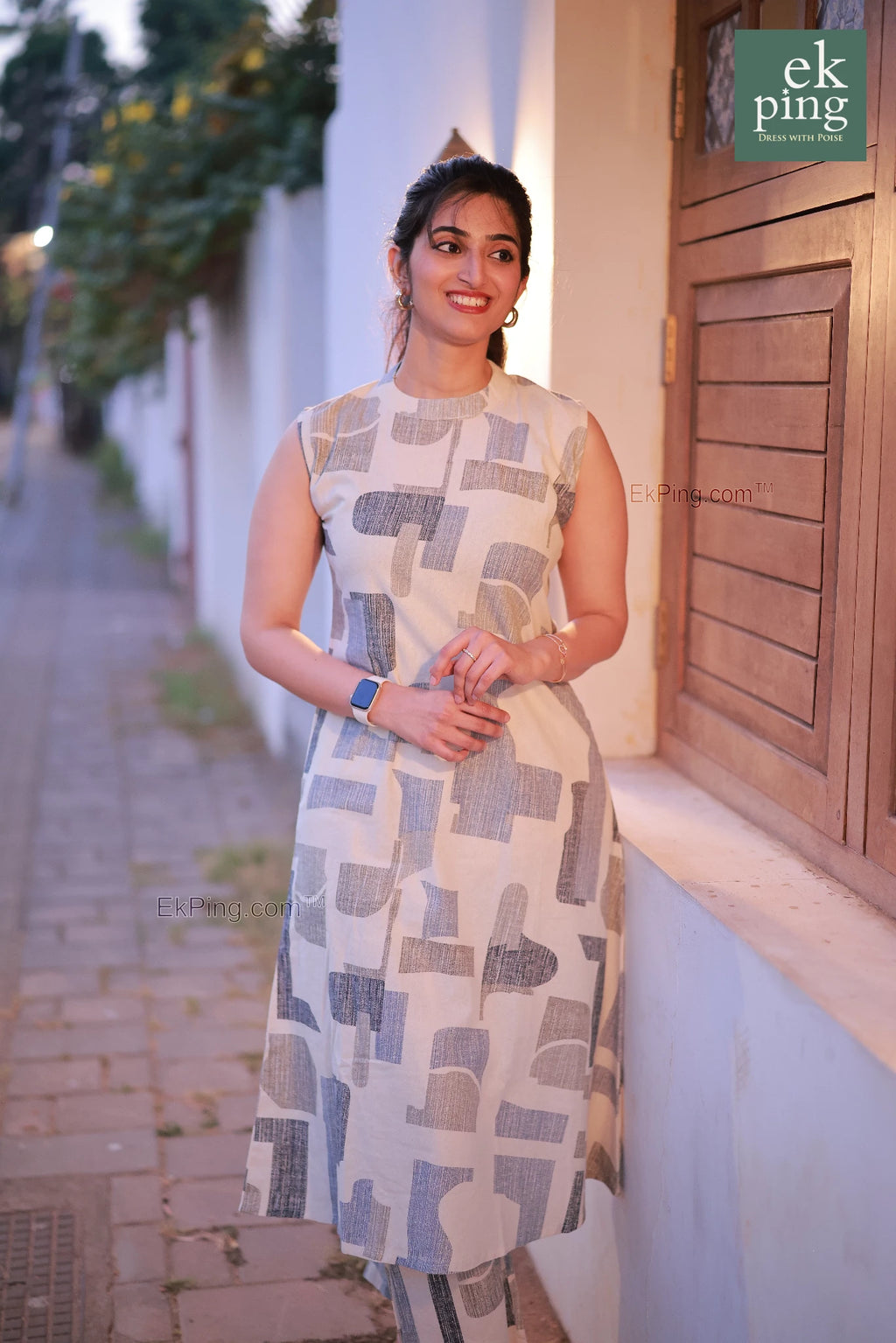 Woman in a white co-ord set dress standing on a street with a building in the background