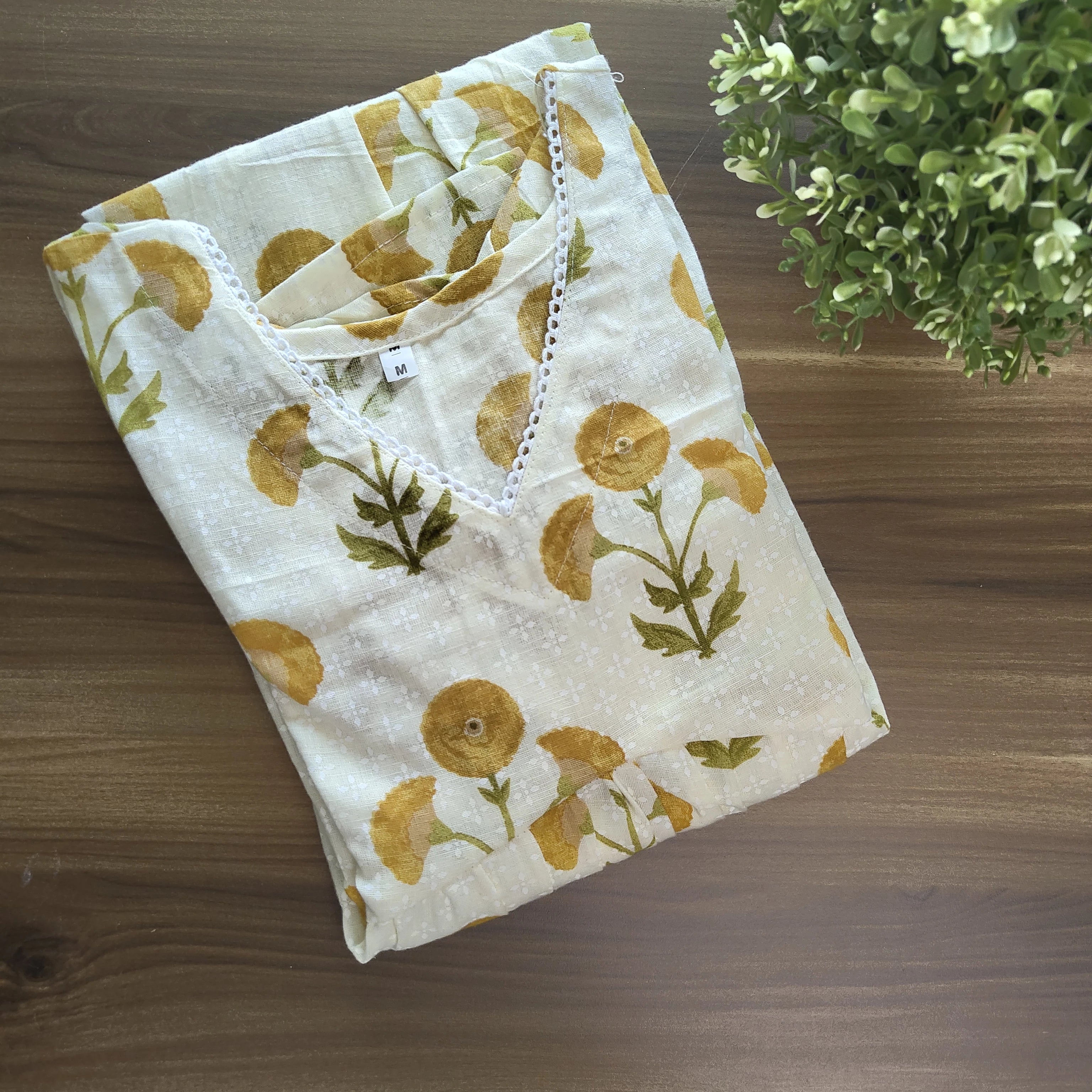 yellow office wear kurti top on a wooden surface with a plant in the corner